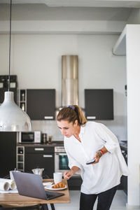 Female entrepreneur working while looking at laptop at home