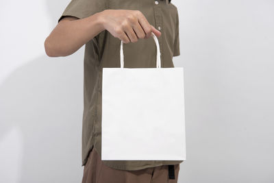 Midsection of person holding paper against white background
