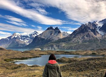 Rear view of woman looking at lake and snowcapped mountain against sky