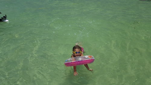 High angle view of little girl with inflatable ring swimming in sea