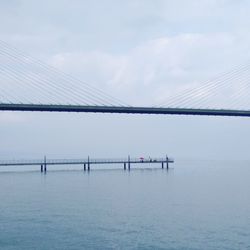 Suspension bridge over sea against sky