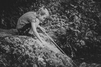 Side view of boy crouching on rock