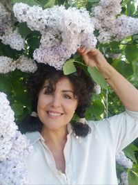 Portrait of smiling woman with flower petals on plant