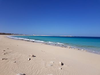 Scenic view of beach against clear blue sky
