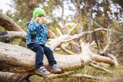 Portrait of young man sitting on tree trunk