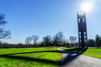 Trees on grassy field against blue sky