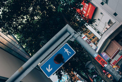 Low angle view of road sign by building in city