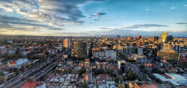 Aerial view of modern buildings in city against sky during sunset