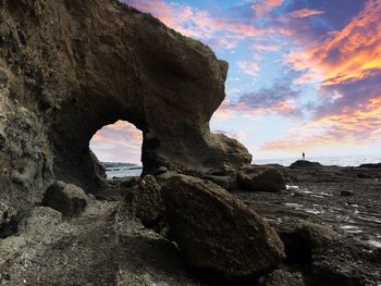 Rocks on sea shore against sky during sunset