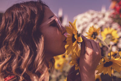 Close-up of young woman holding flower in ornamental garden at dusk