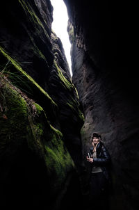 Man standing on cliff by cave