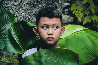 Portrait of young boy cover with leafs