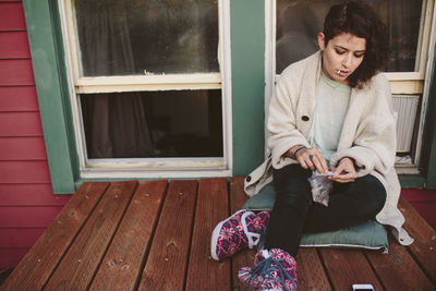 High angle view of woman making marijuana joint while sitting on rooftop