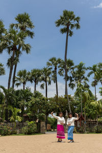 Woman with palm trees against sky