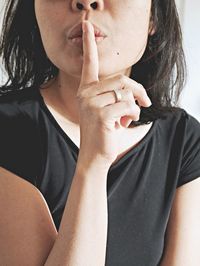 Midsection of woman with finger on lips