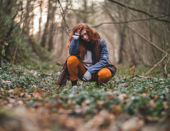 Surface level of woman crouching in forest