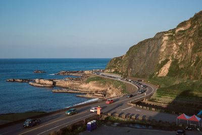 High angle view of road by sea against clear blue sky