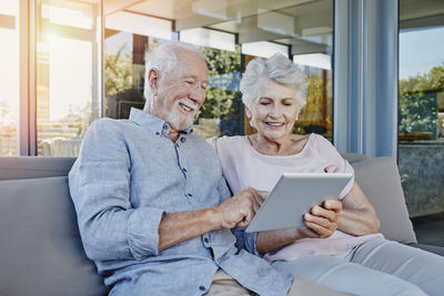 Senior couple sitting on terrace using digital tablet