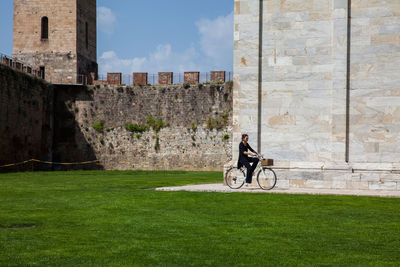 Man riding bicycle on street against building