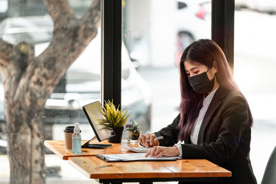 Woman using phone while sitting on table