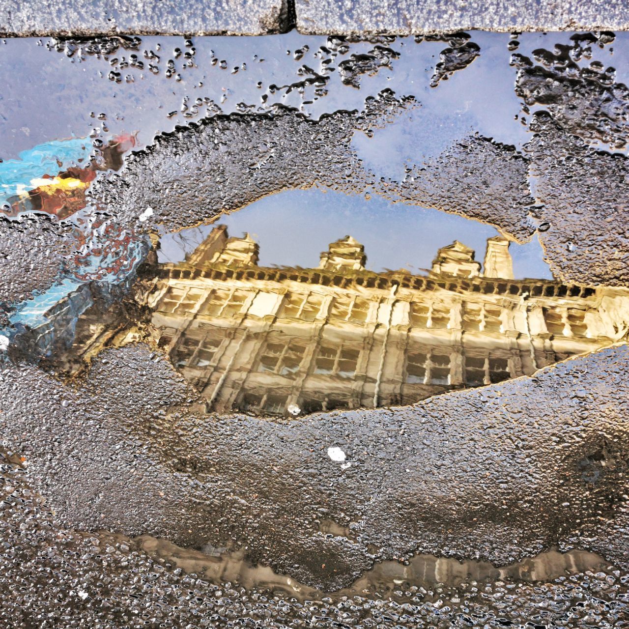 REFLECTION OF BUILDING ON PUDDLE IN STREET