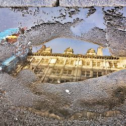 Reflection of building in puddle on street