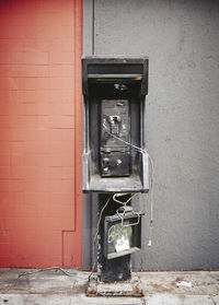 Abandoned telephone booth against wall