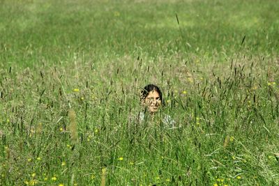 Smiling girl sitting amidst plants on field