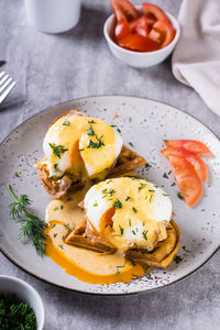 Delicious homemade breakfast with waffles, bacon and eggs benedict on a plate. vertical view