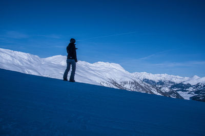 Woman standing on snowcapped mountain against sky