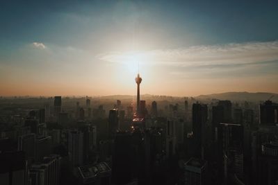 Modern buildings in city against sky during sunset