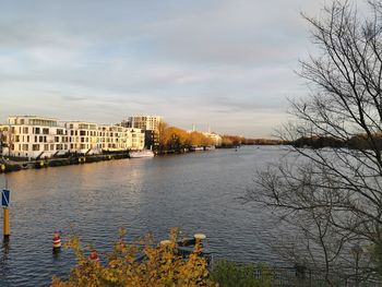 Scenic view of river by buildings against sky