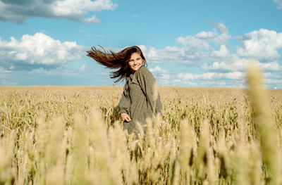 Young woman standing on field against sky