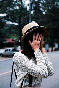 Young woman covering face while standing on street