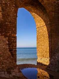 Arch in sea against clear sky