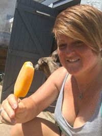 Portrait of woman having popsicles while standing in yard