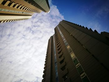 Low angle view of office building against cloudy sky