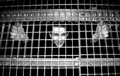 Portrait of man looking through fence