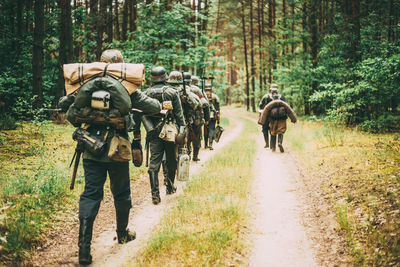 Rear view of soldiers walking on trail in forest