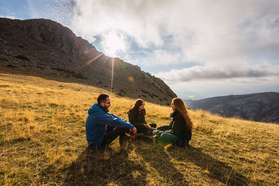 People sitting on mountain against sky