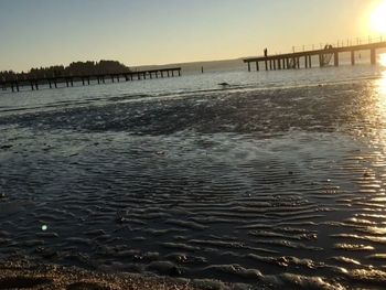 Pier on sea against clear sky at sunset