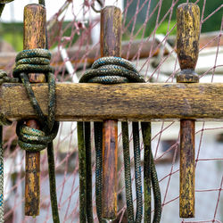 Close-up of ropes tied up to wooden railing