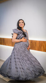 Portrait of young woman standing against wall and turning around. pregnant women 