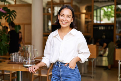 Portrait of young woman standing in cafe