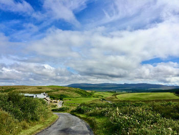 Road amidst field against sky