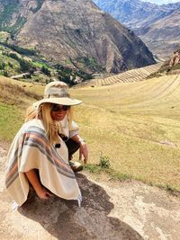 Midsection of woman sitting on landscape against mountains