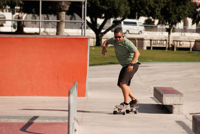 Man riding skateboard in urban street skatepark. casual guy wearing shorts and t-shirt.