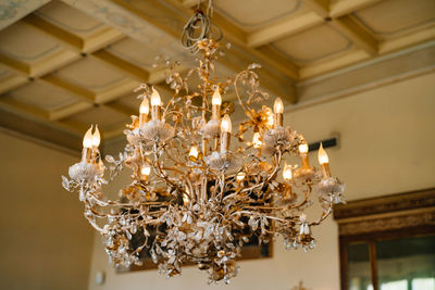 Low angle view of illuminated chandelier hanging on ceiling