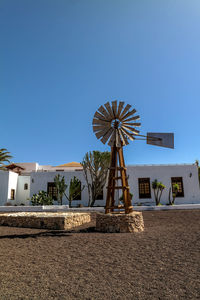 Low angle view of windmill against clear blue sky