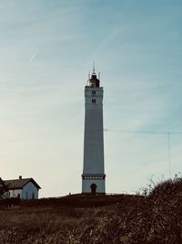 Lighthouse by sea against sky